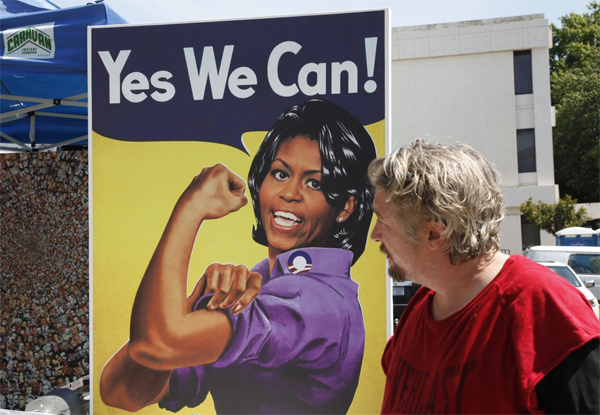 image of a white male artist standing next to one of his pieces in which Rosie the Riveter has been reimagined as First Lady Michelle Obama saying, 'Yes We Can.'