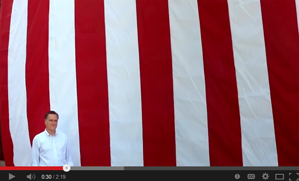 image of Mitt Romney standing in front of a humongous US flag